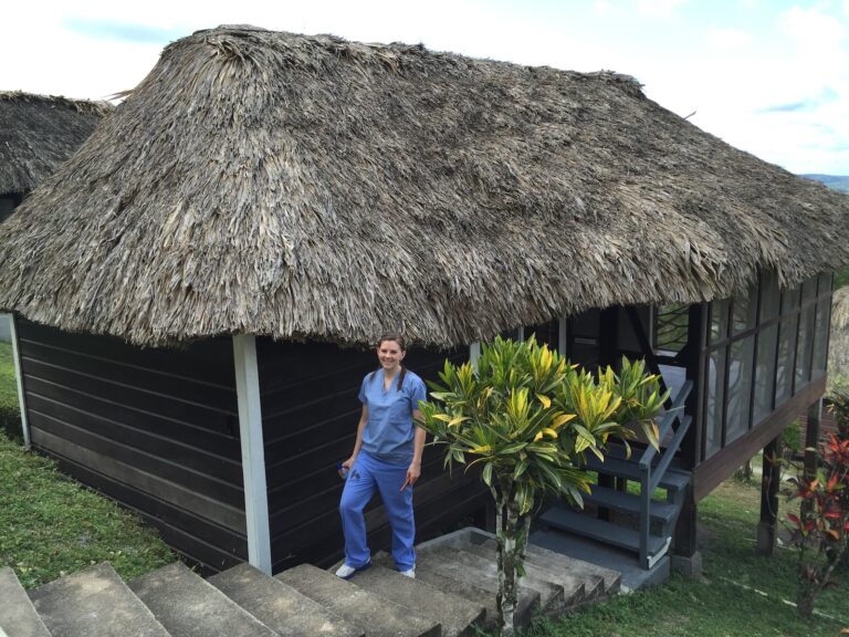 Humanitarian Projects Team member outside of a hut with a grass roof